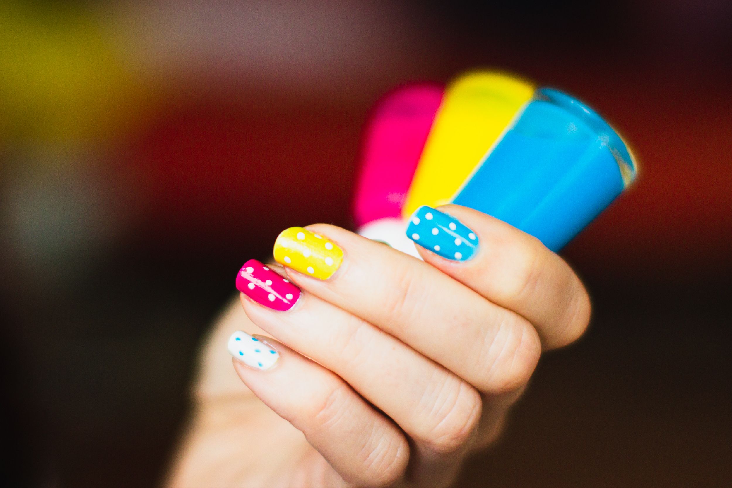 Main vernis à ongles colorés pois vibrants