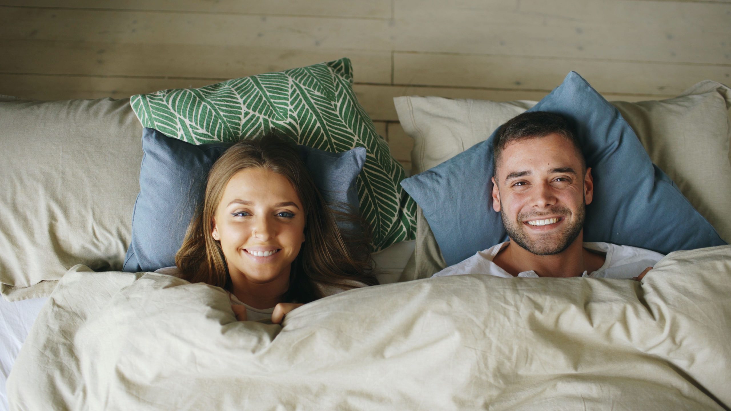 Couple souriant au réveil dans lit confortable
