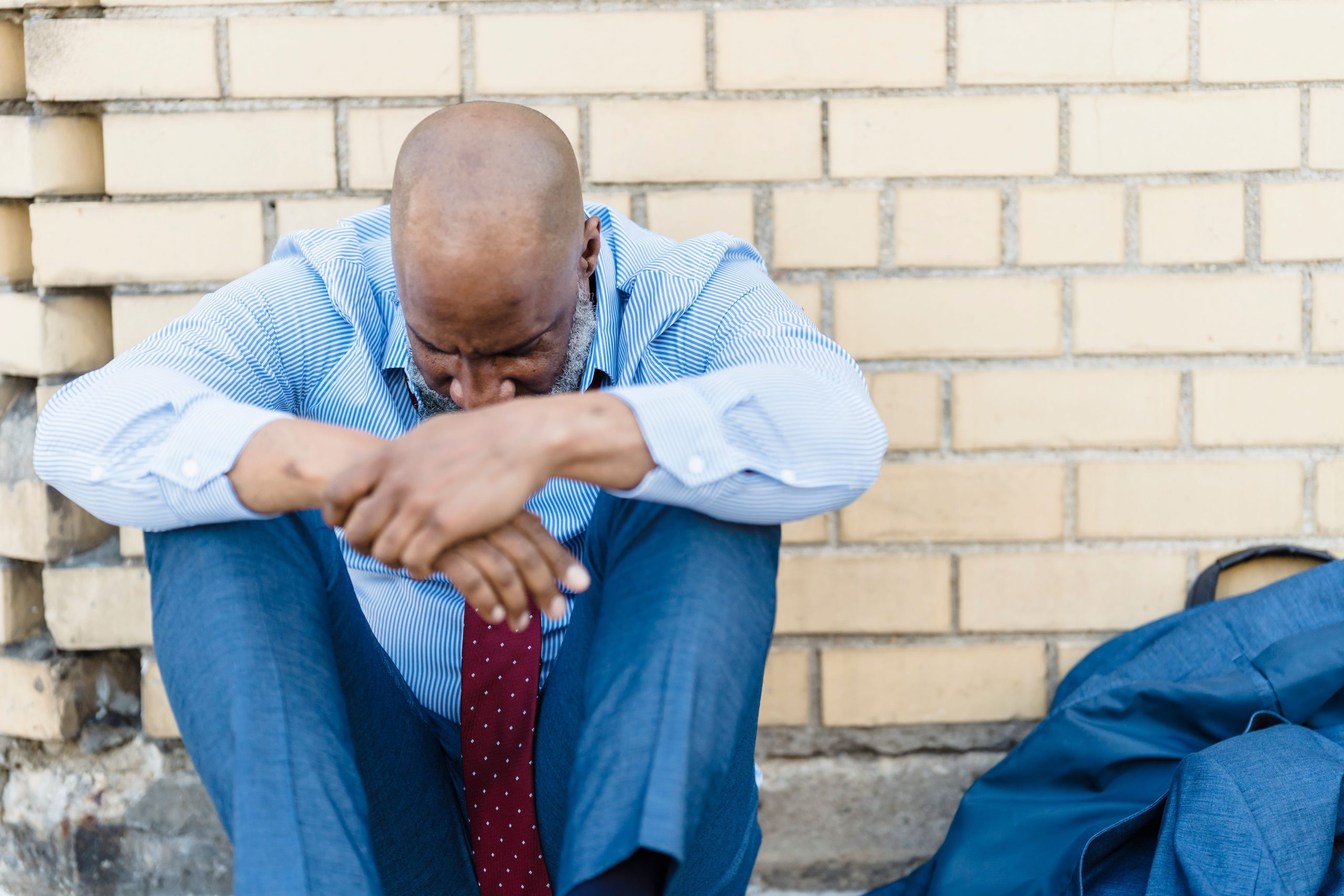 Homme triste pleurant seul contre mur brique