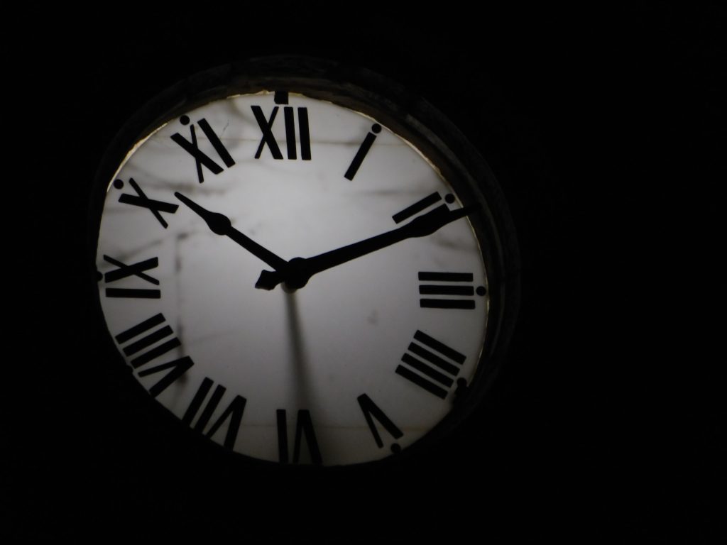 Horloge mécanique ronde avec aiguilles noires sur fond obscur