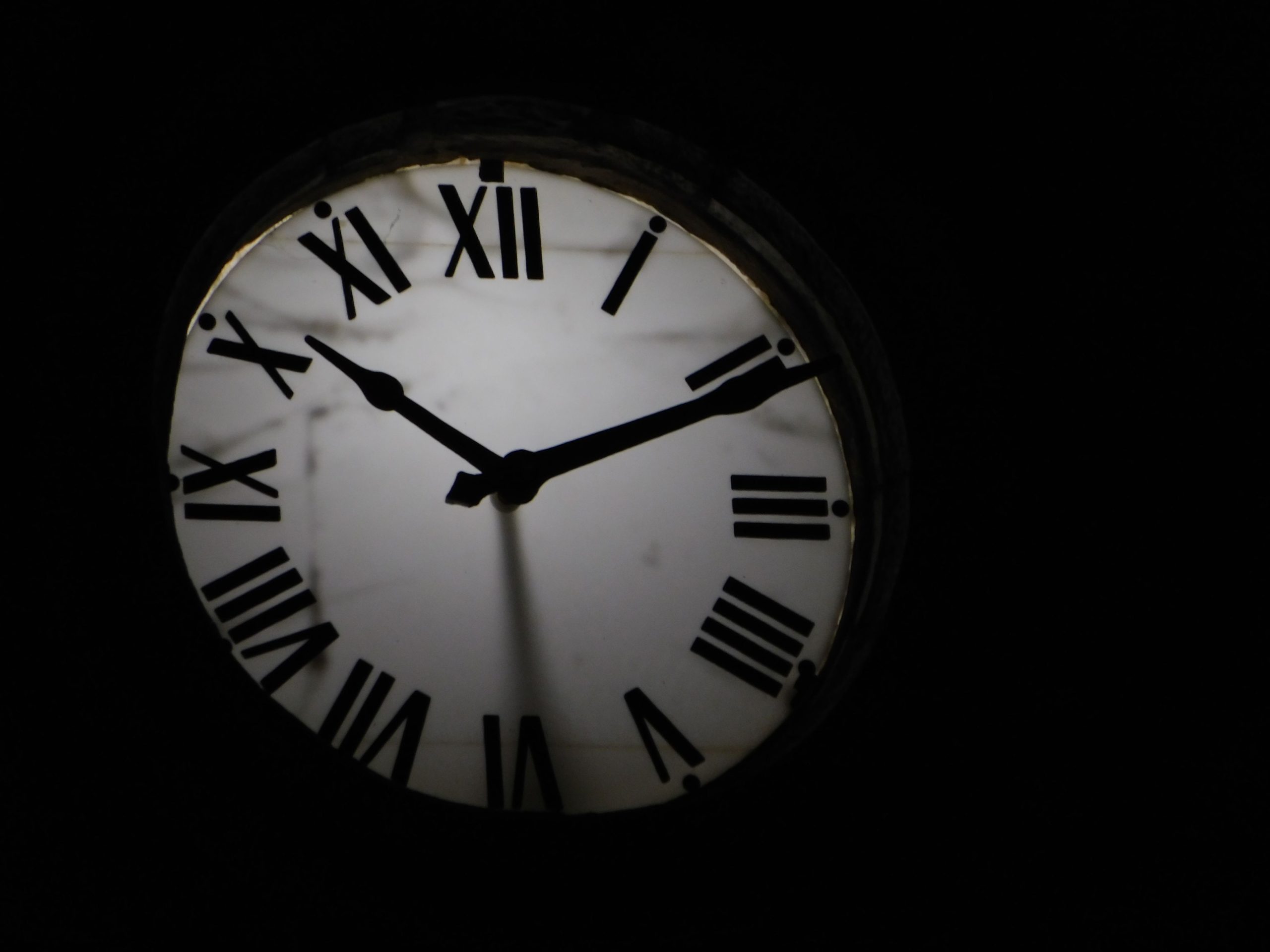Horloge mécanique ronde avec aiguilles noires sur fond obscur