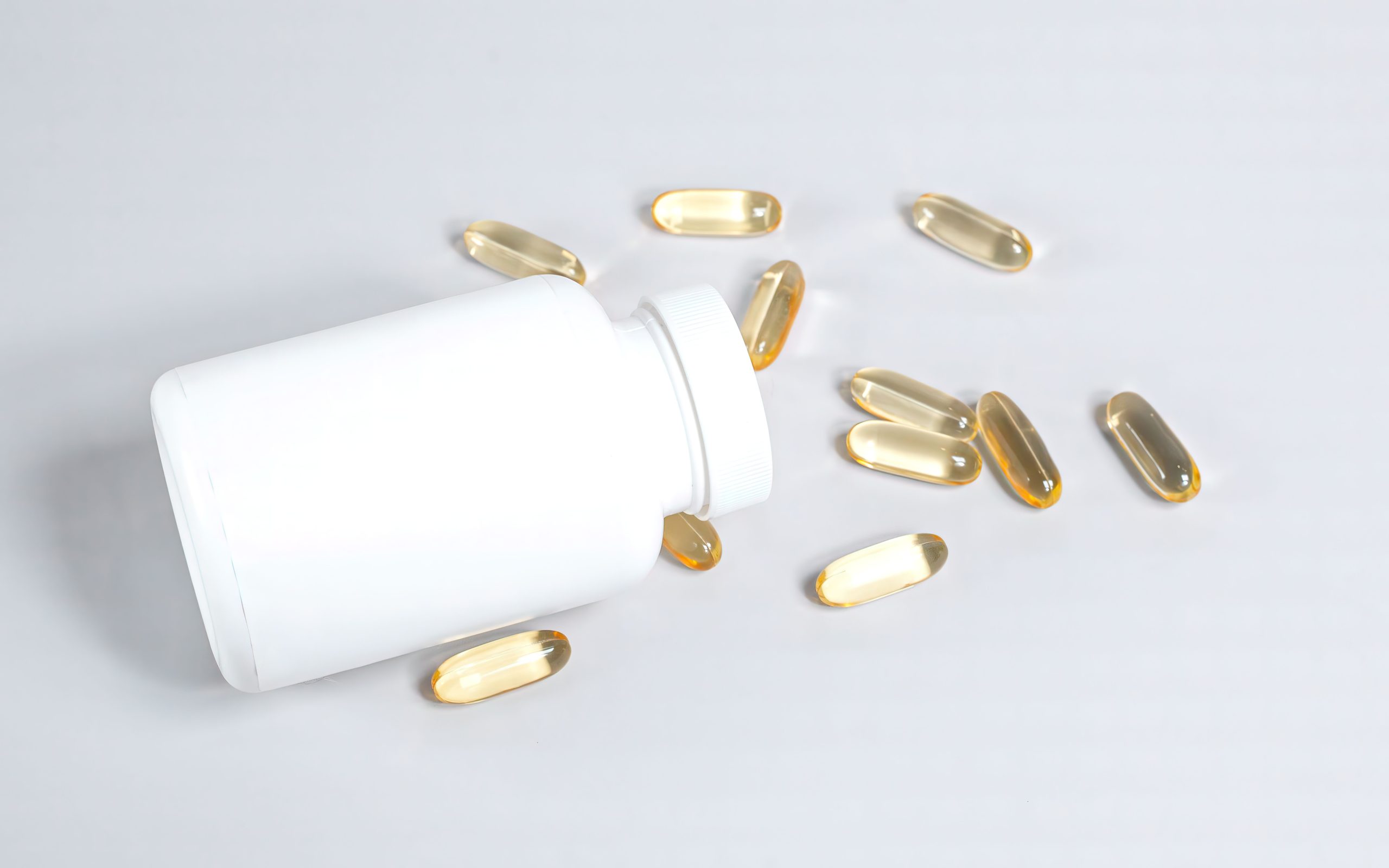Capsules oméga-3 versées d'un flacon blanc