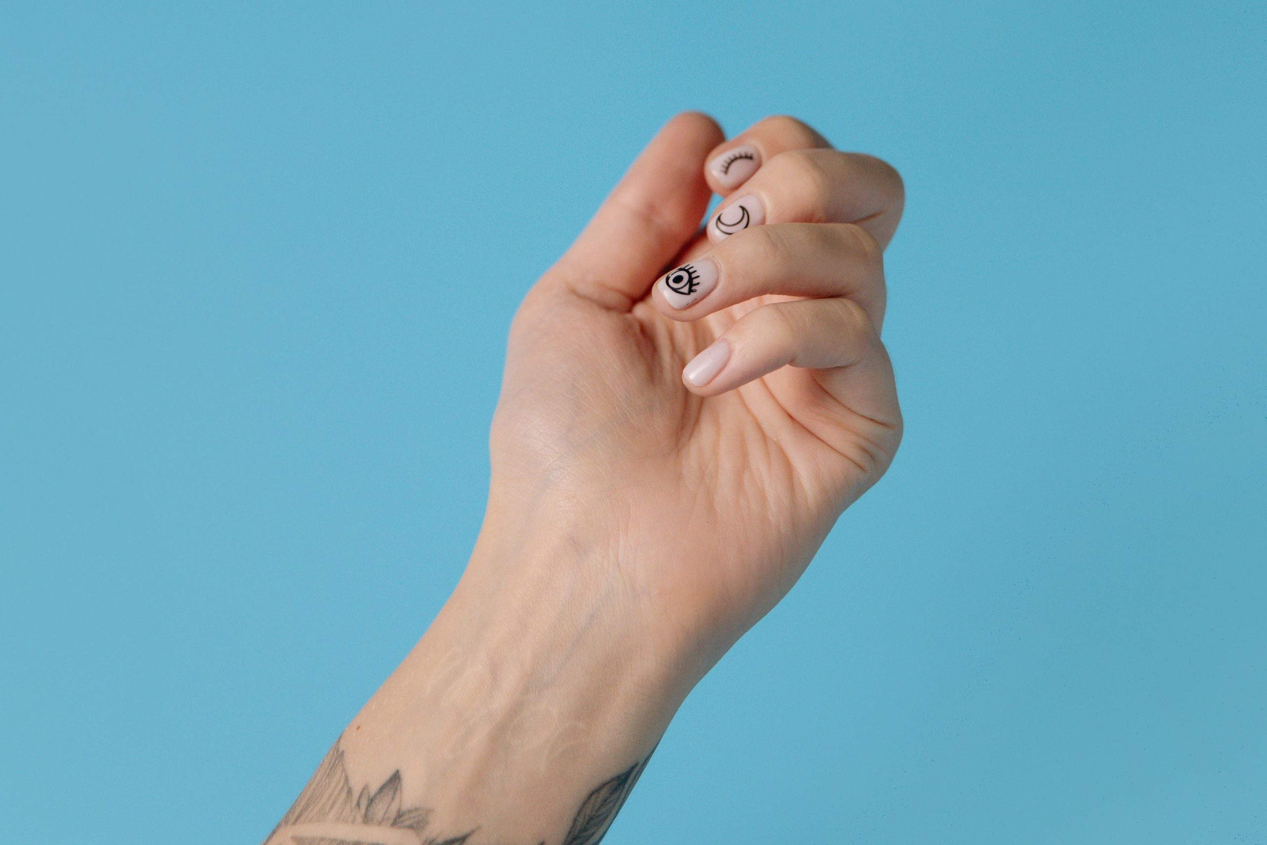 Main tatouée avec nail art créatif bleu