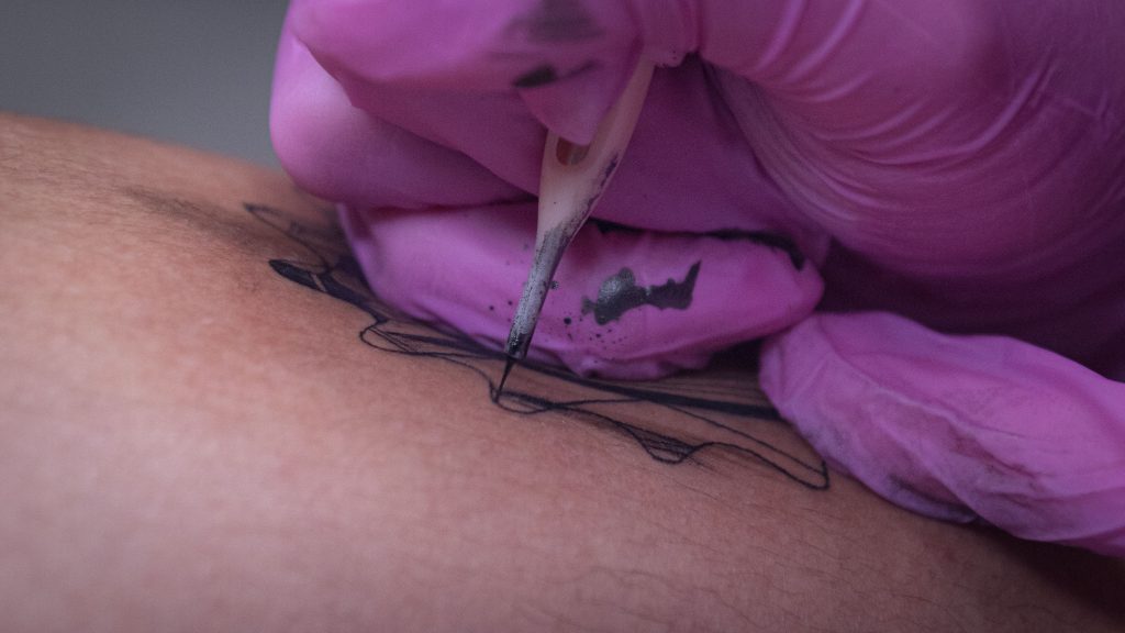 Gros plan d'un tatoueur encrant un design sur la peau