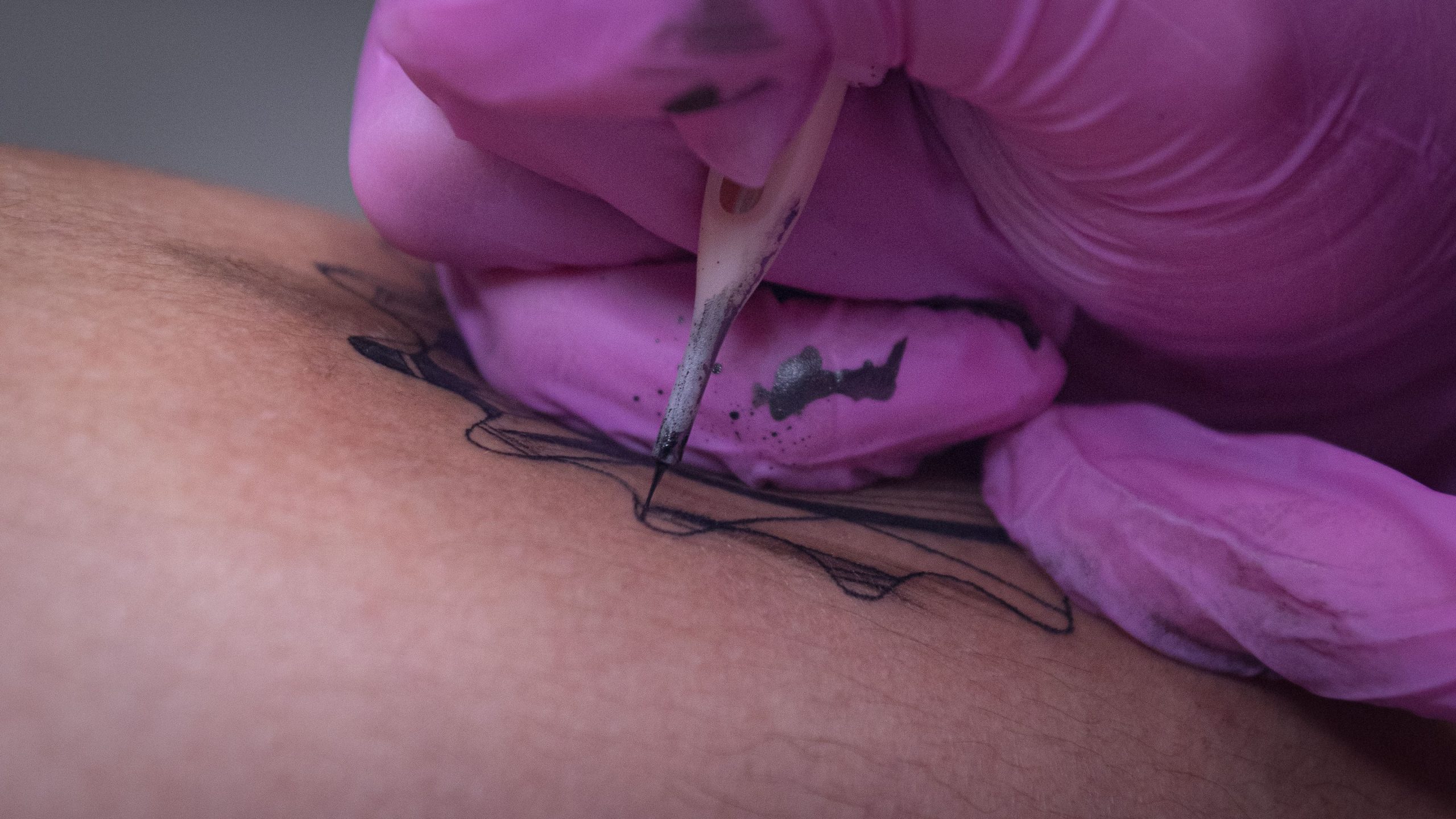 Gros plan d'un tatoueur encrant un design sur la peau