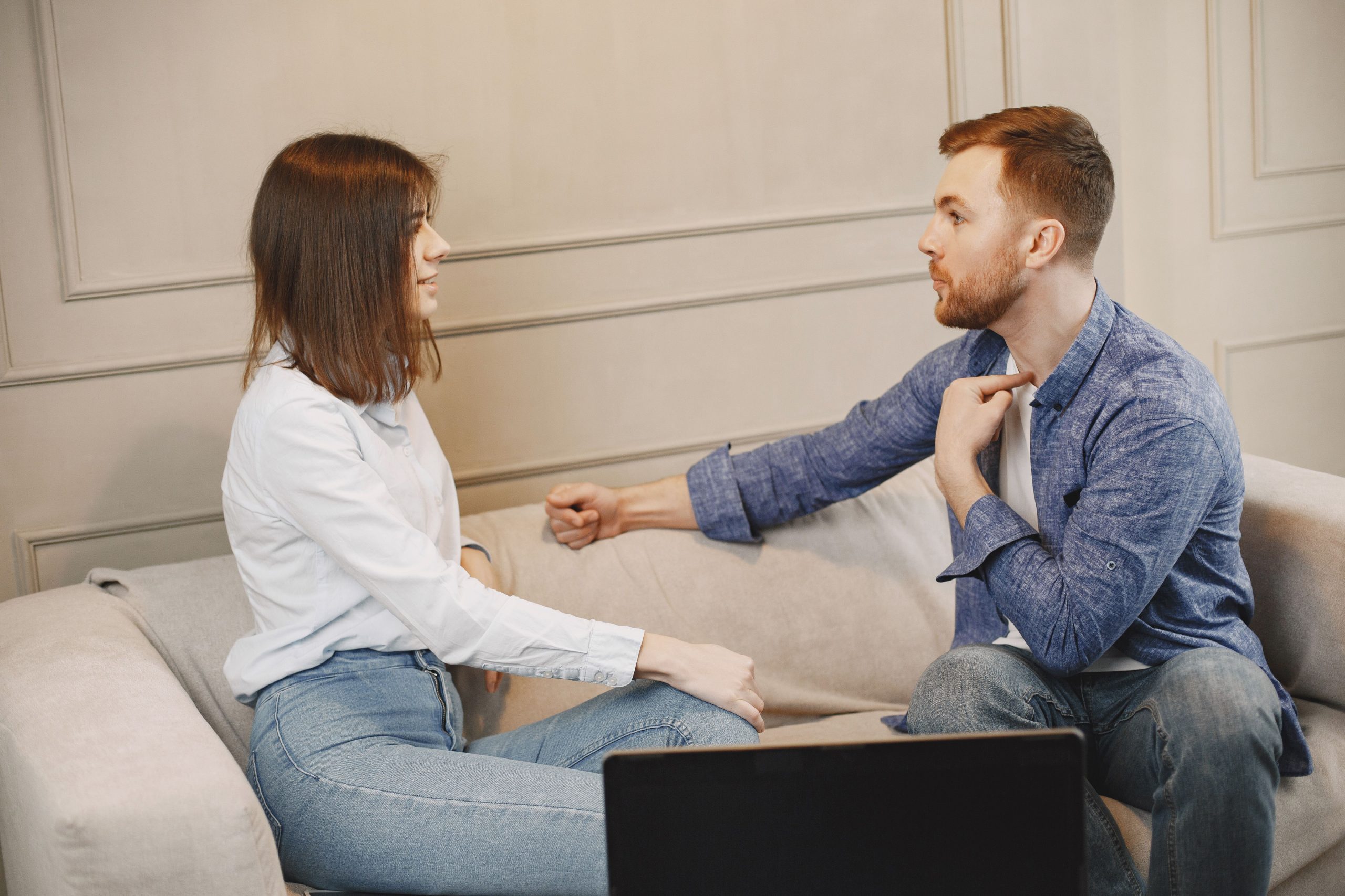 Jeune couple en conversation sur canapé beige