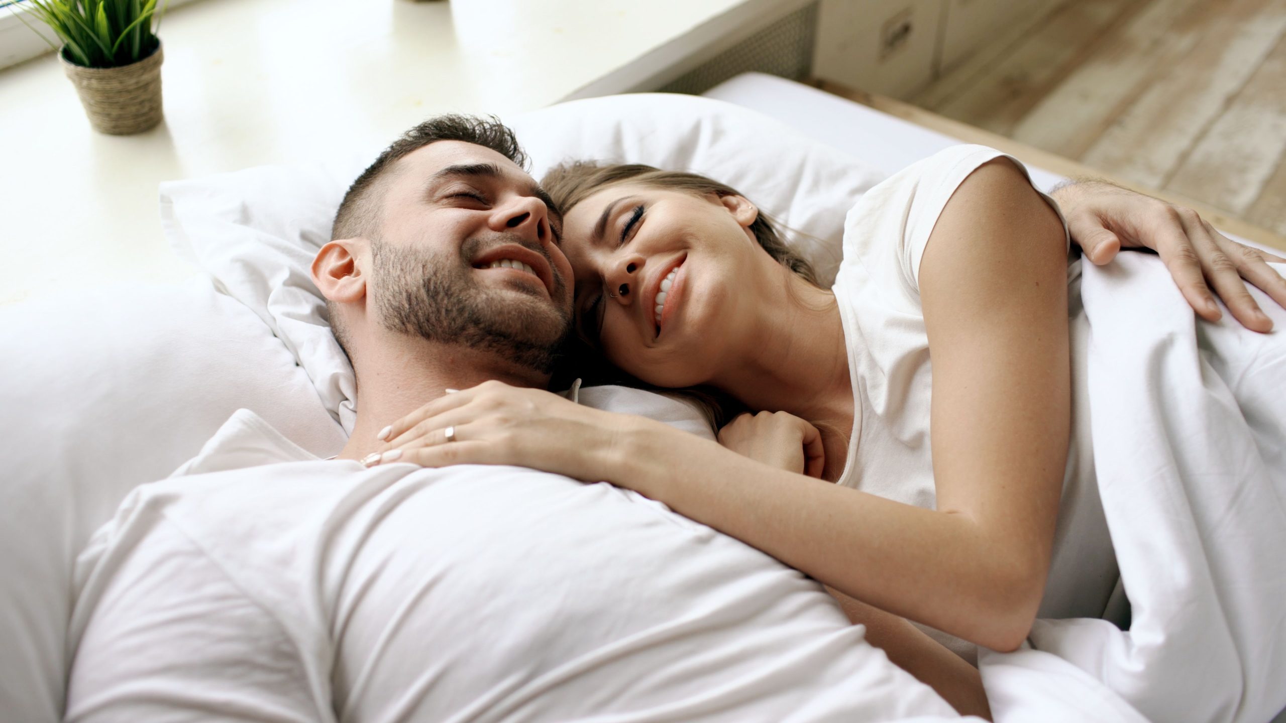 Couple joyeux se câlinant au lit le matin