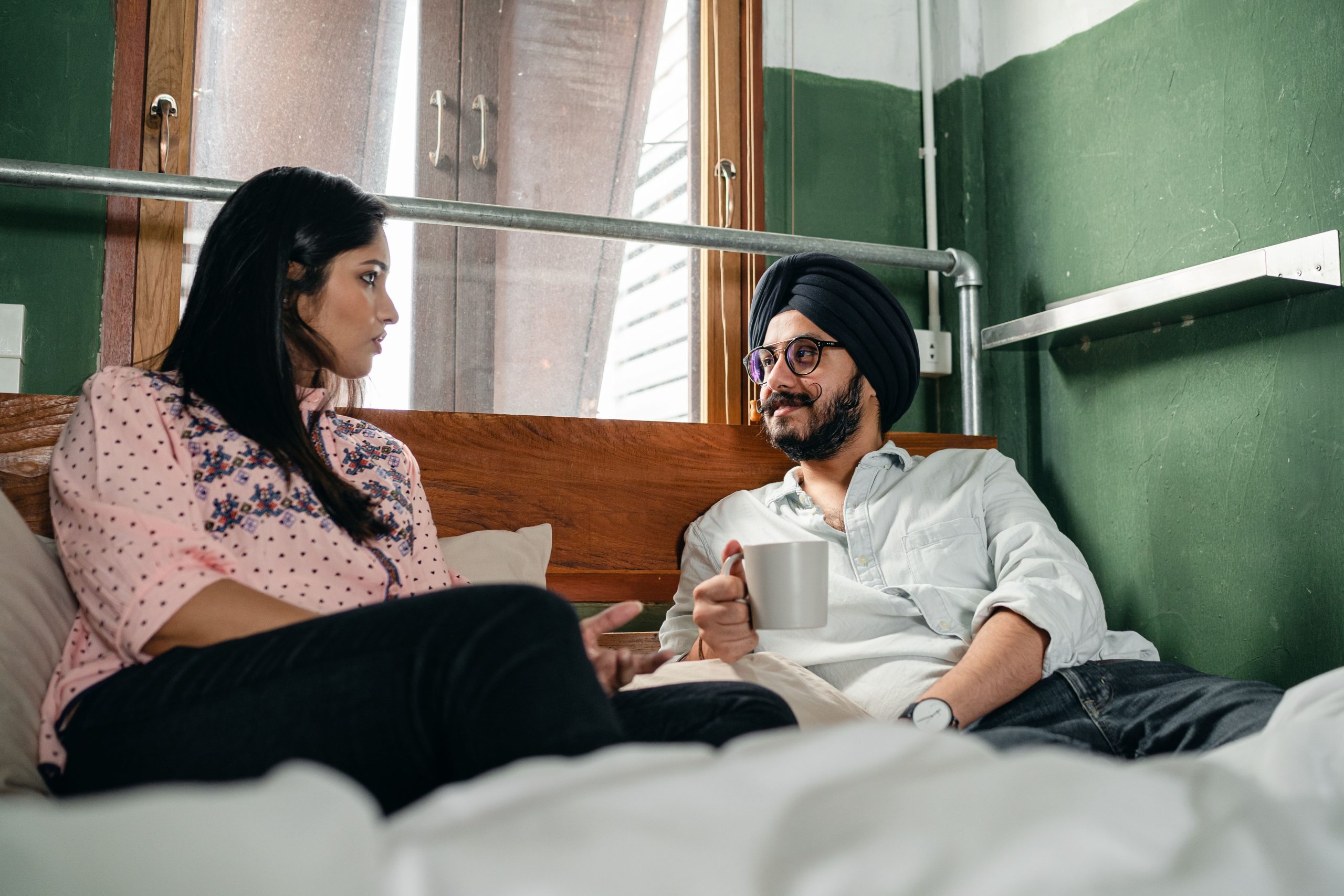Couple souriant discutant ensemble sur lit