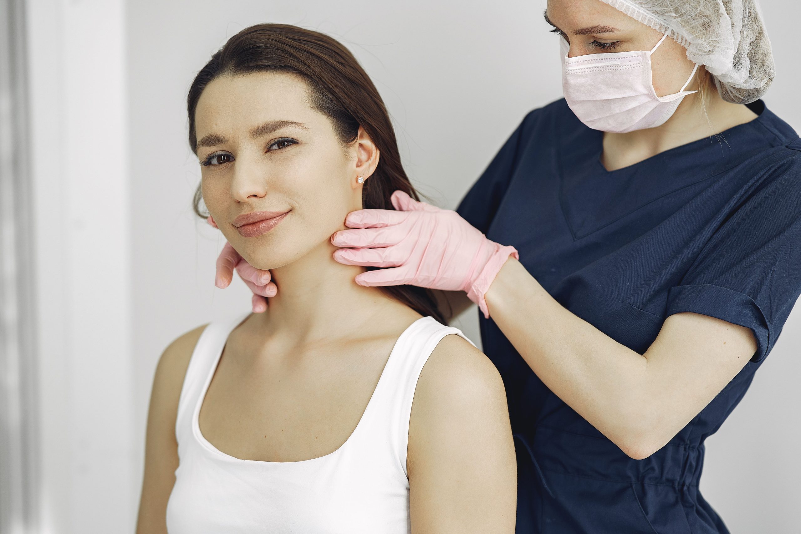 Praticien examinant le cou d'une patiente souriante