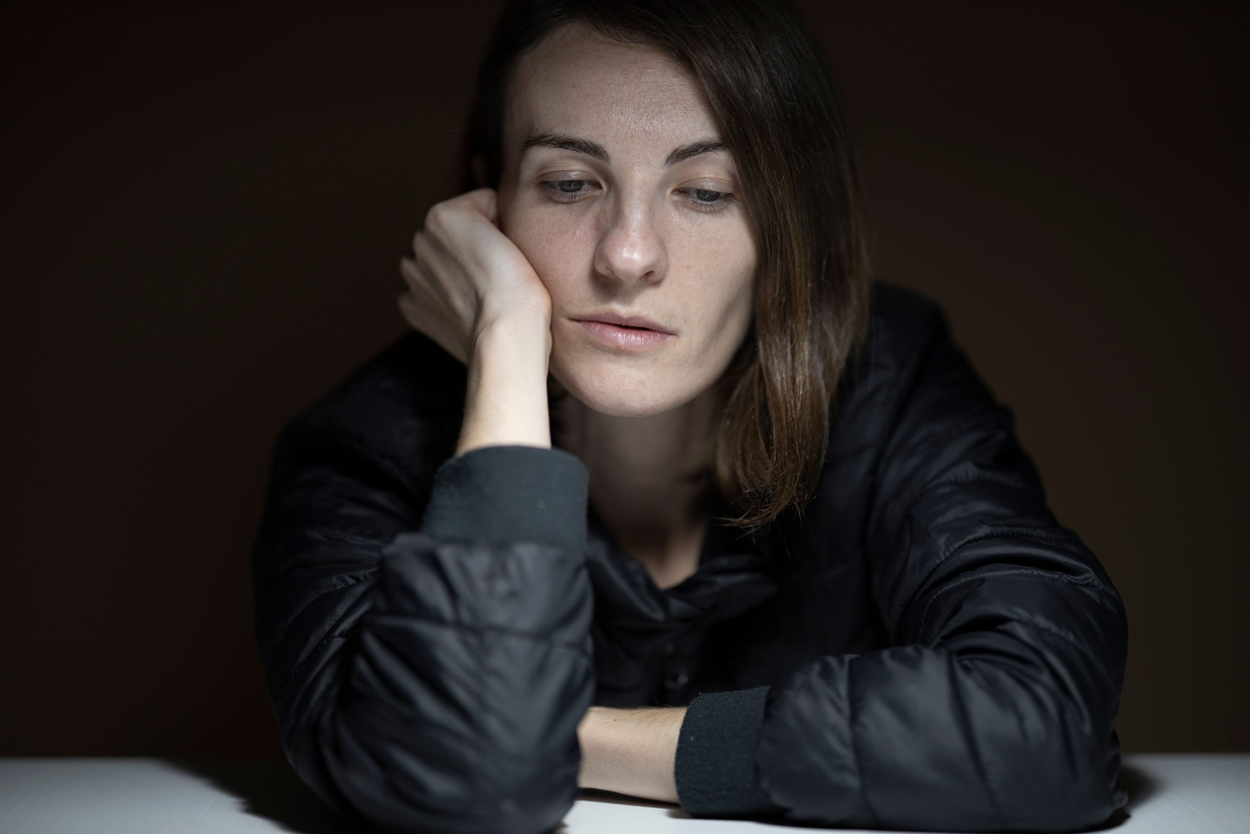 Femme pensive avec une expression serieuse dans l'obscurite