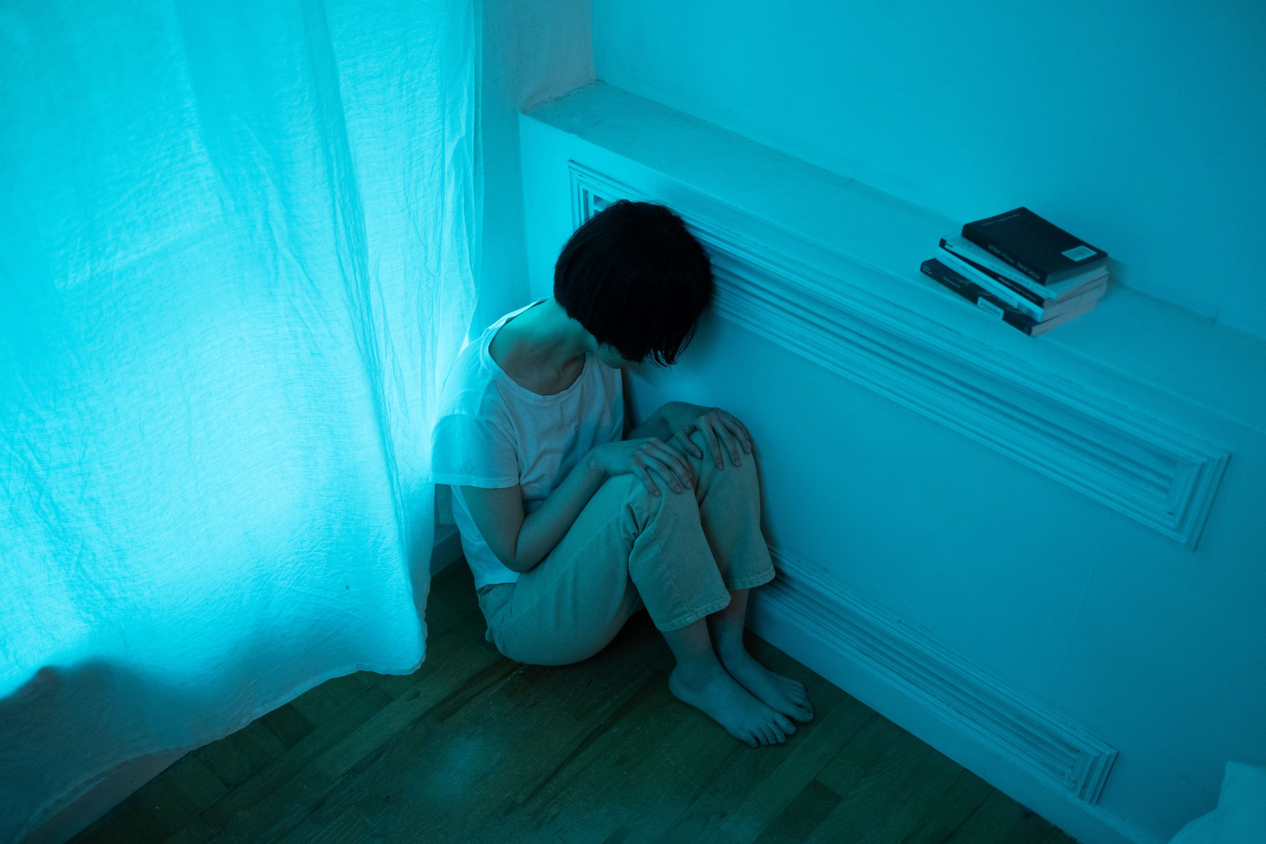 Femme seule dans une chambre sombre exprimant de la solitude