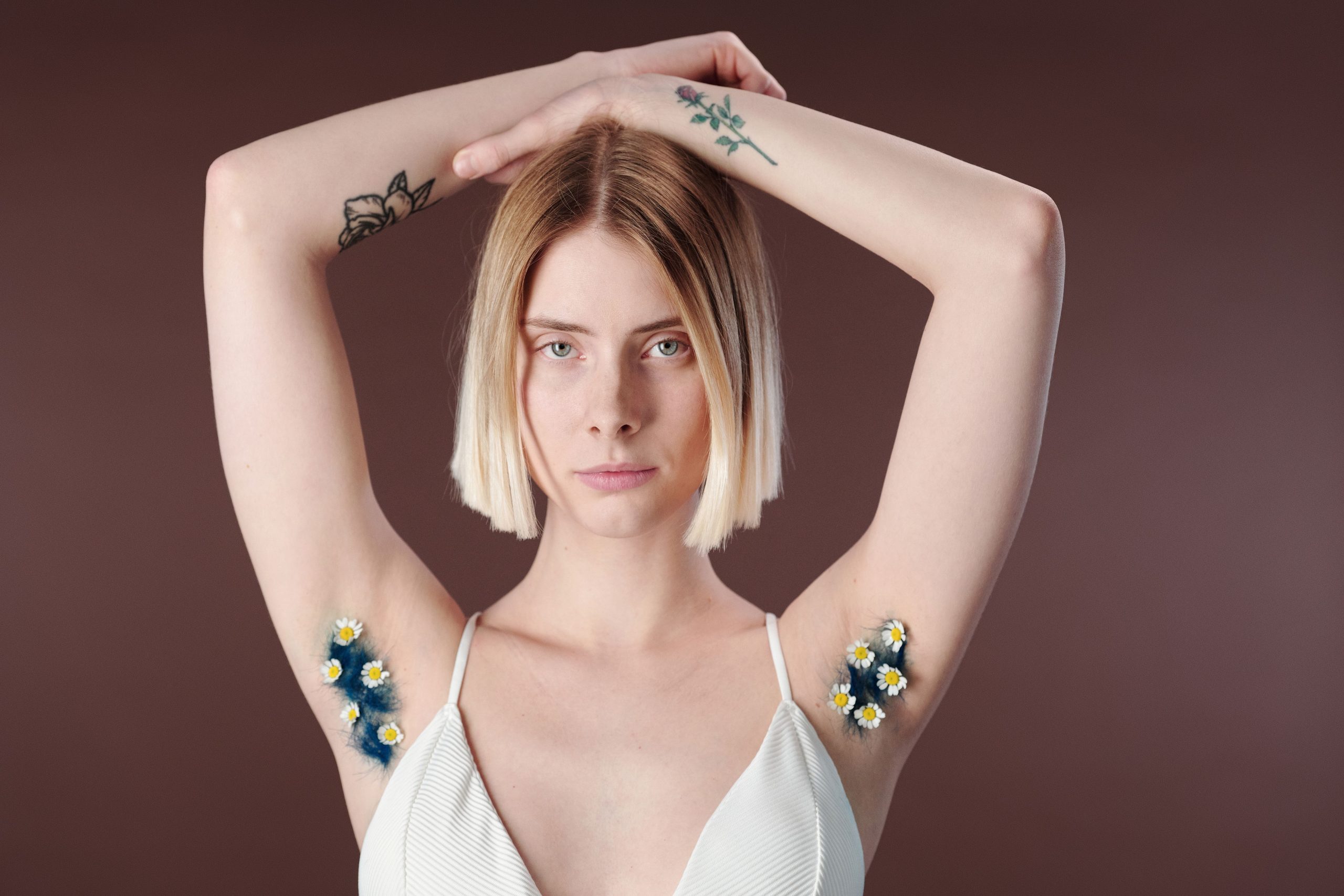 Jeune femme tatouages bras levés fleurs