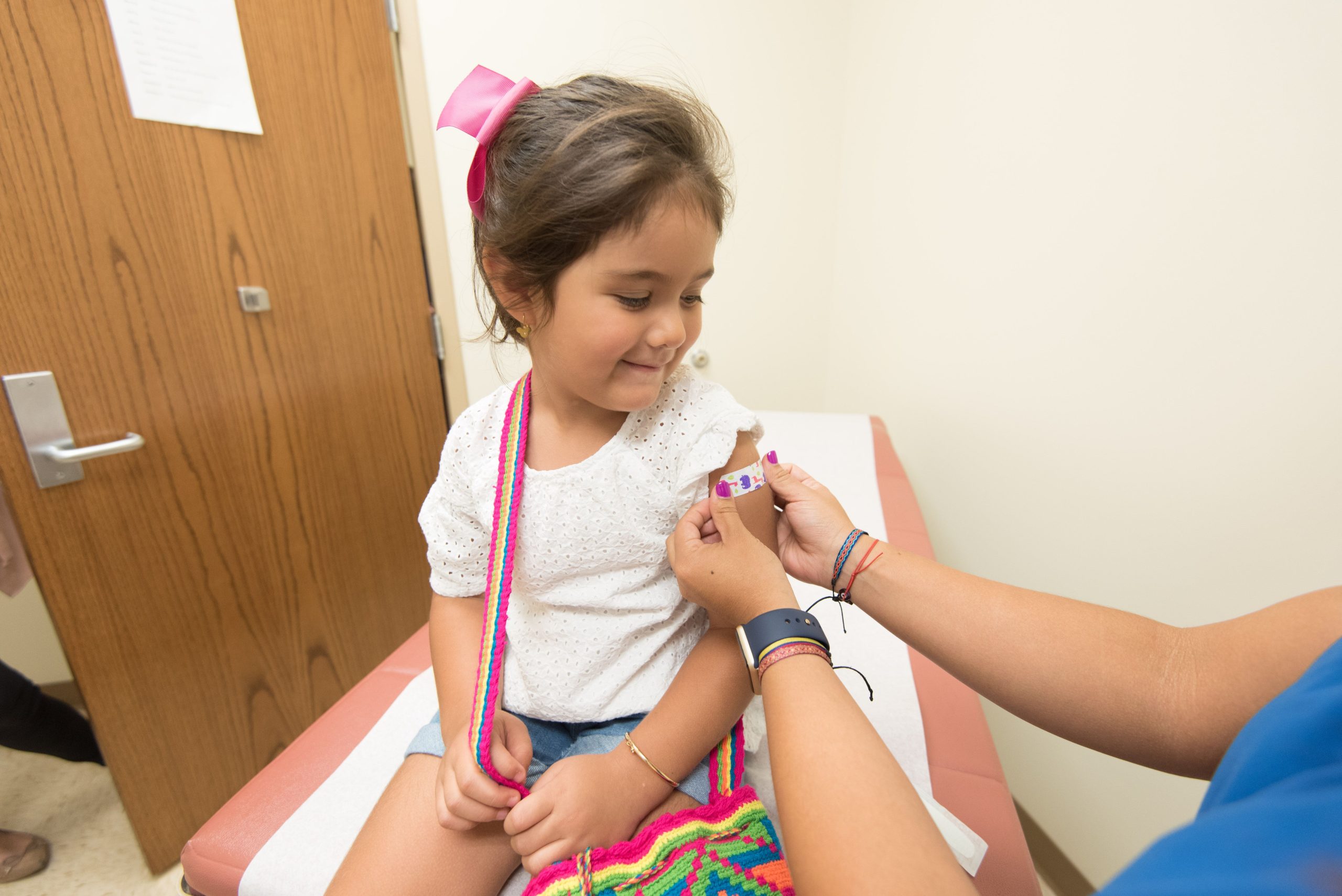 Petite fille souriante recevant un pansement après vaccination